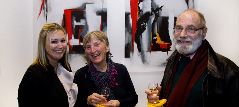 Gäste und Künstlerin Bianca Lardi bei Kunstausstellung mit abstrakten Werken im Hintergrund