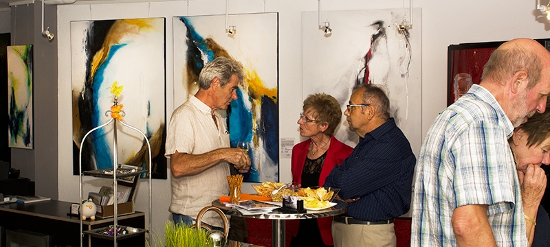 Gäste bei Kunstausstellung mit abstrakten Werken im Hintergrund