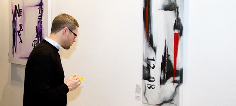 Gast bei Kunstausstellung mit abstrakten Werken im Hintergrund