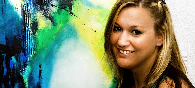 Künstlerin Bianca Lardi vor abstraktem Acrylbild bei Ausstellung