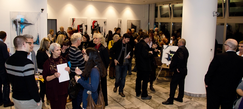 Gäste bei Kunstausstellung mit abstrakten Werken im Hintergrund